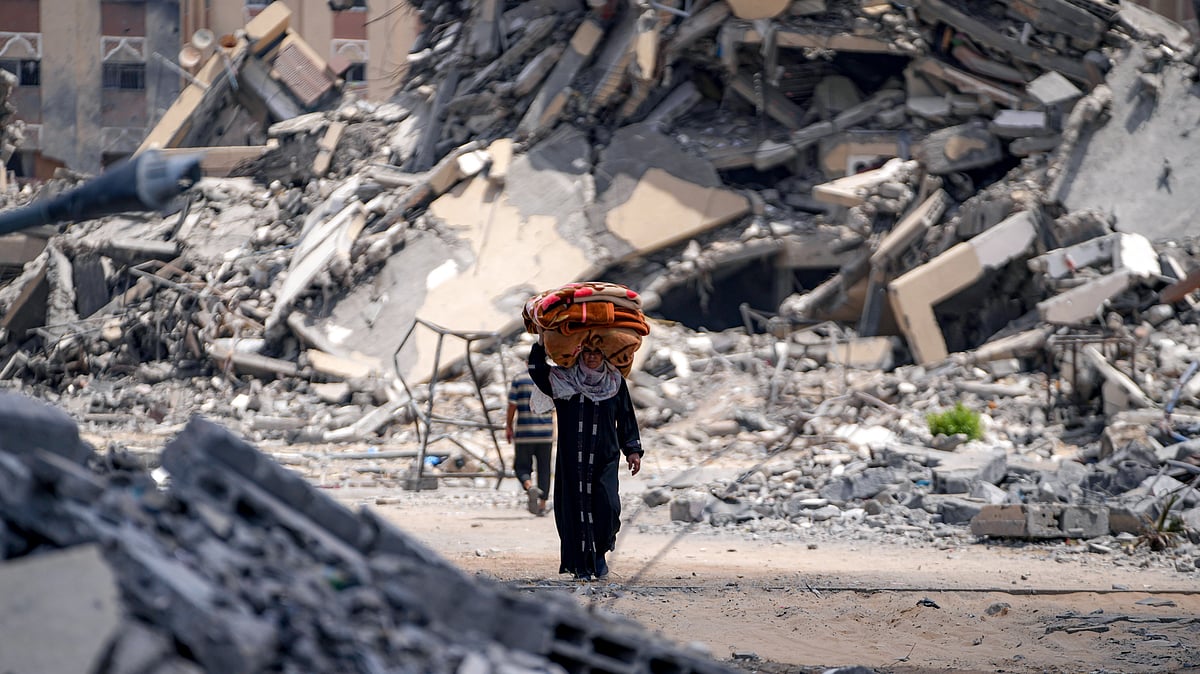 AP : A woman moves with her belongings in a bombed out area of Gaza.